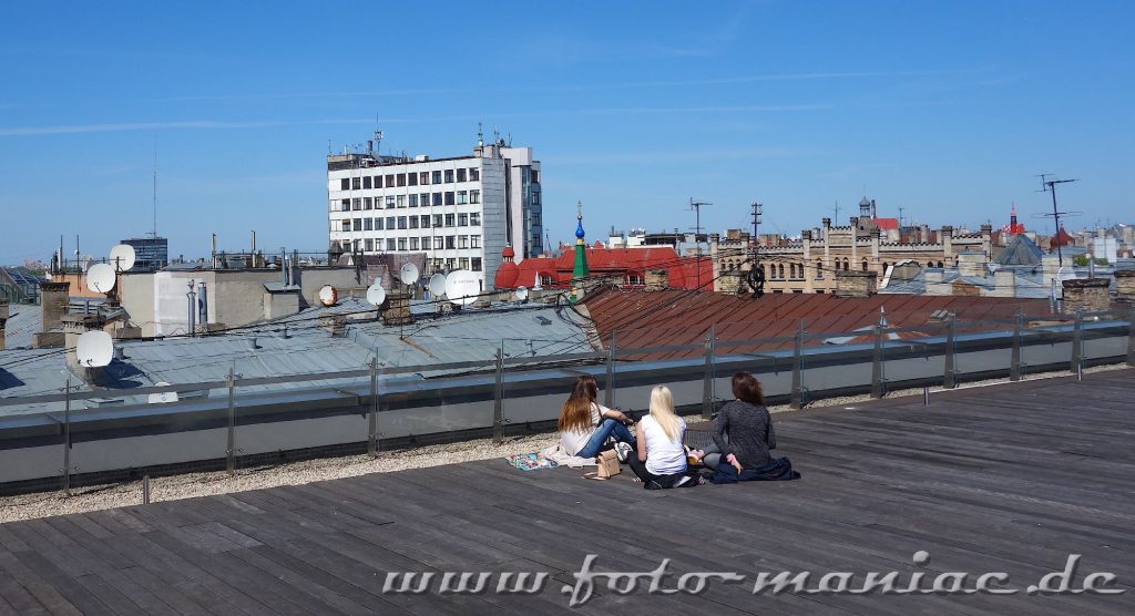 Drei Mädchen sitzen in Riga auf einem Dach