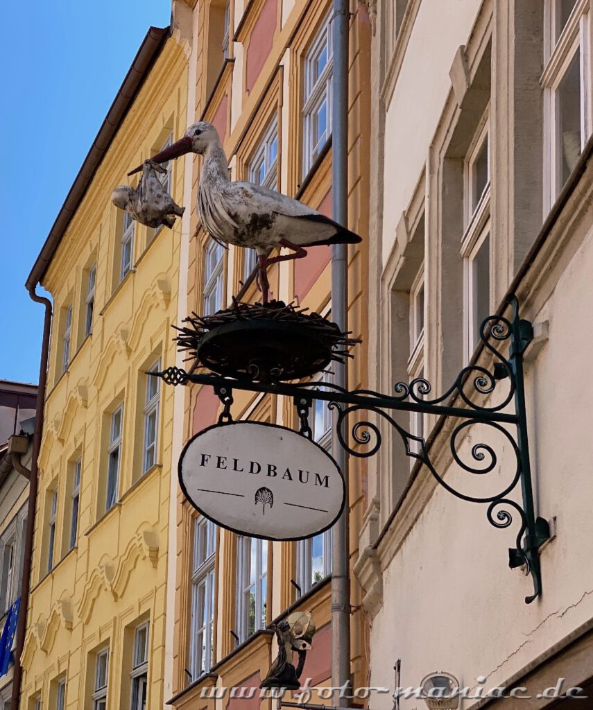 Storch auf Ladenschildausleger an einer Hauswand in Bamberg