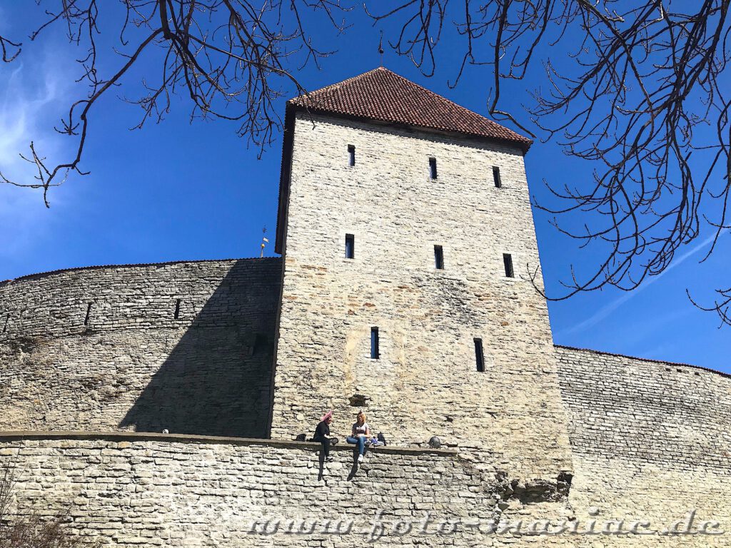 Zwei Mädchen sitzen auf einem Mauervorsprung an der Burg in Tallinn