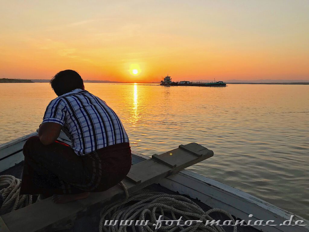 Ein Mann schaut sich vom Boot aus den Sonnenuntergang auf dem Ayeyarwady an