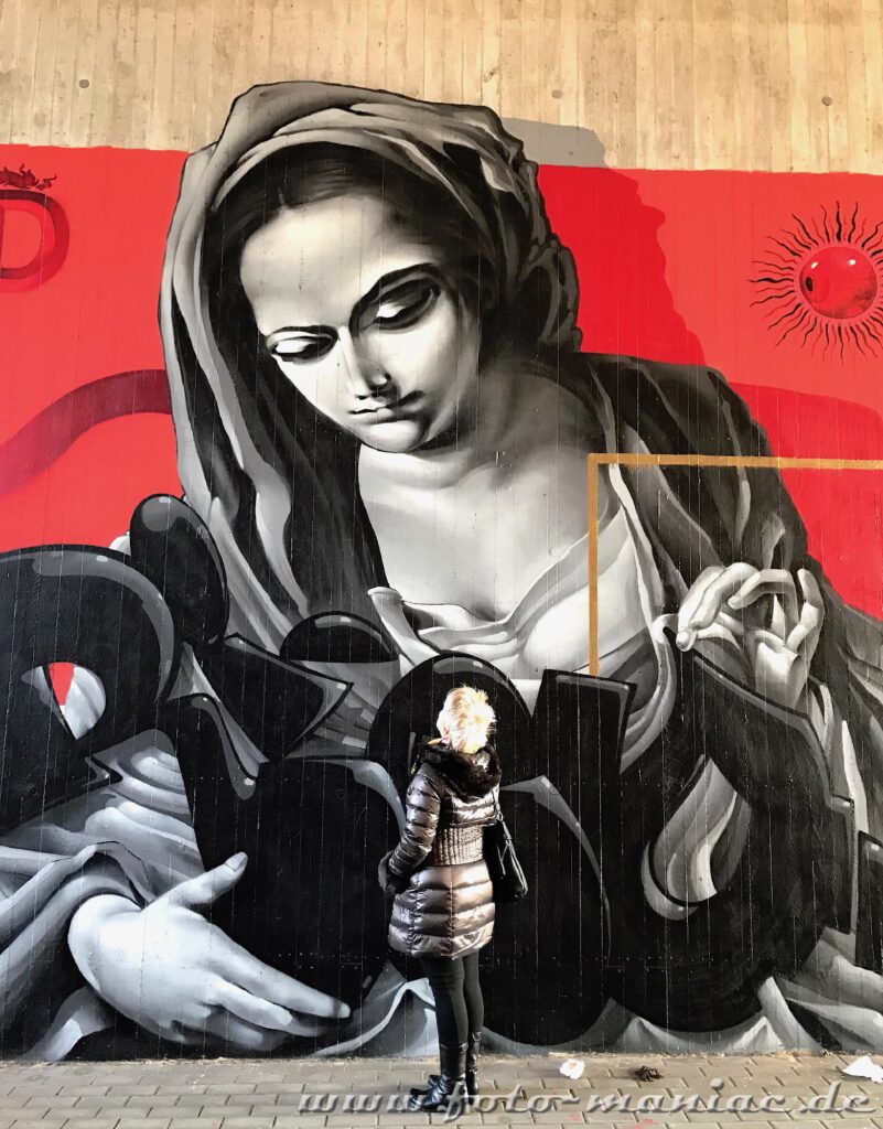 Frau schaut zu einem Madonna-Graffito auf