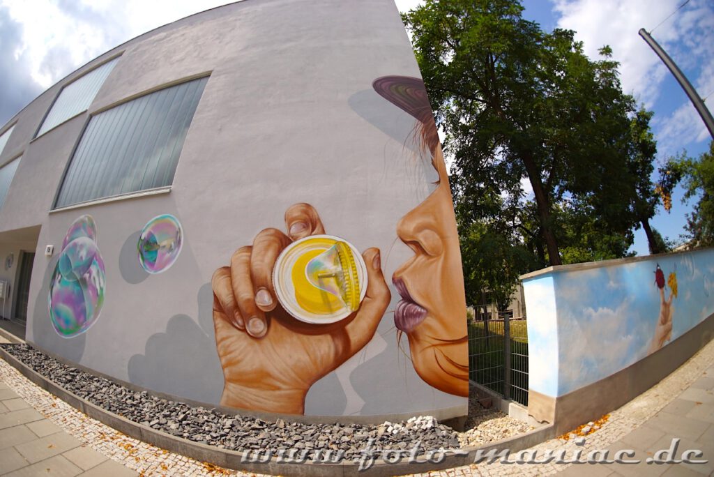 Mauer-Graffito: Kind bläst Seifenblasen in die Luft