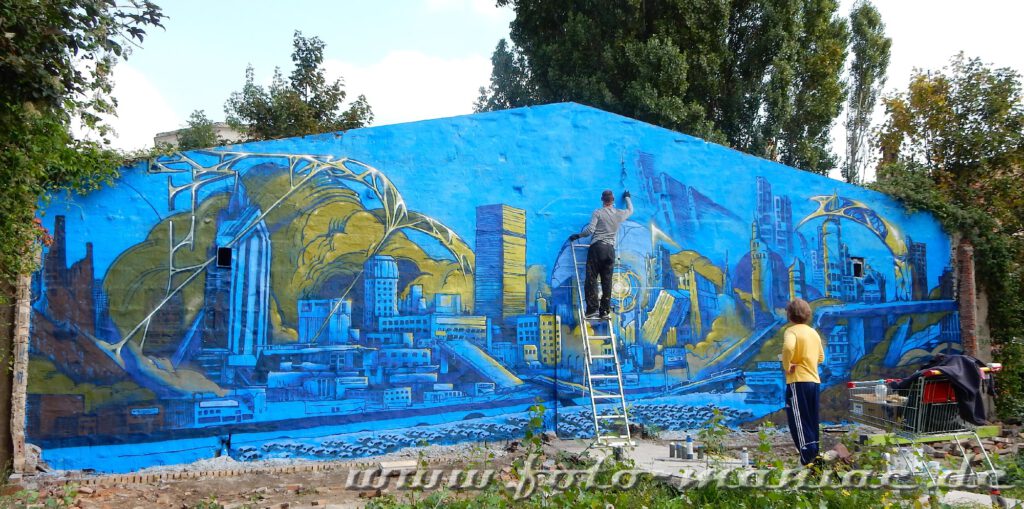 Ein Künstler steht auf der Leiter und arbeitet an seinem Graffiti-Bild