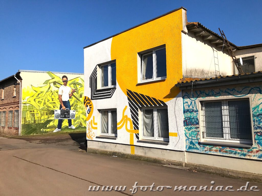 Mural mit Augen mit Radio, daneben Graffiti-Haus