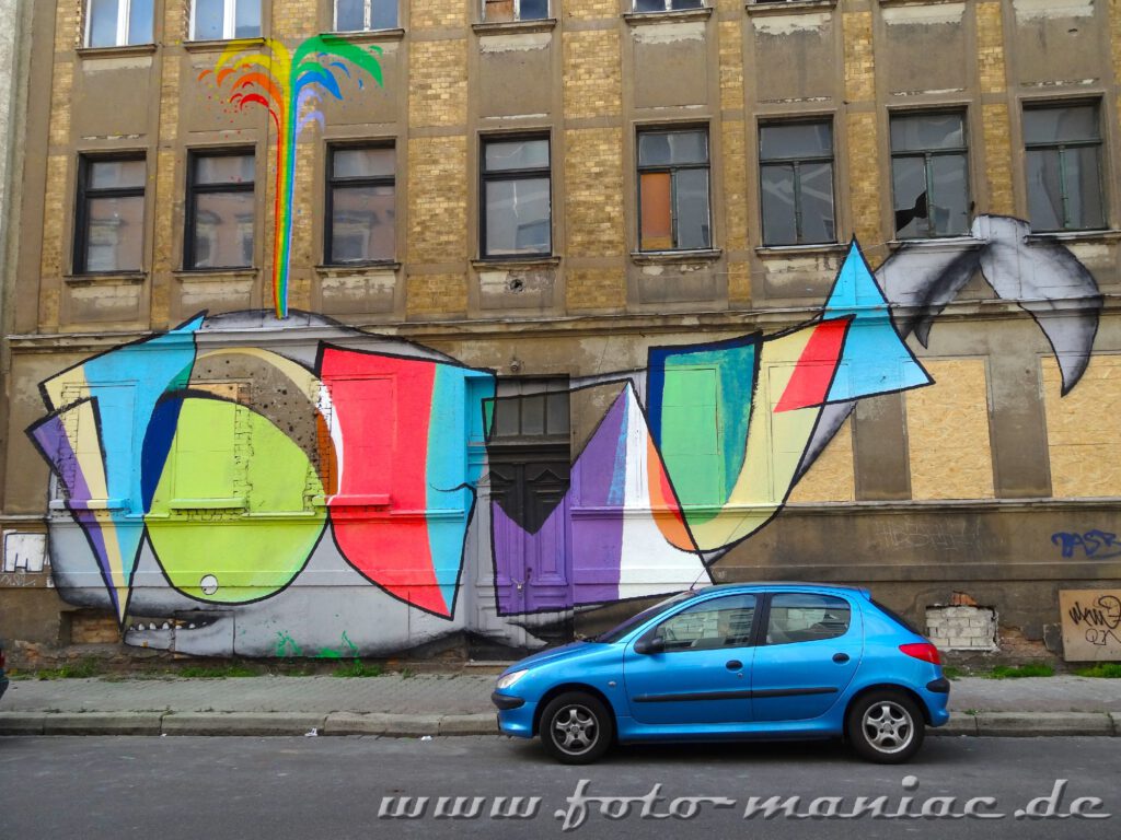 Ein Auto steht vor einem Haus mit buntem Graffito