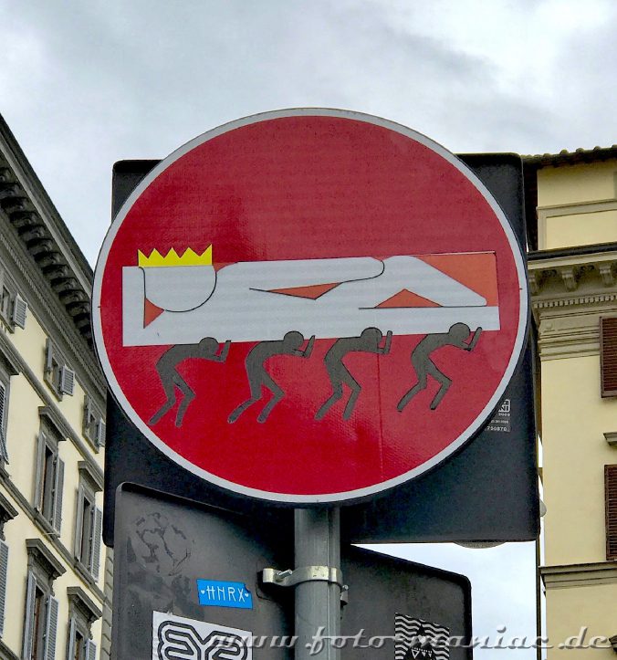 Verkehrsschilder zum Schmunzeln liegender König wird von vier Männern getragen