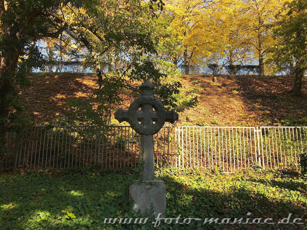 Ein Grabkreuz vor einem Zaun