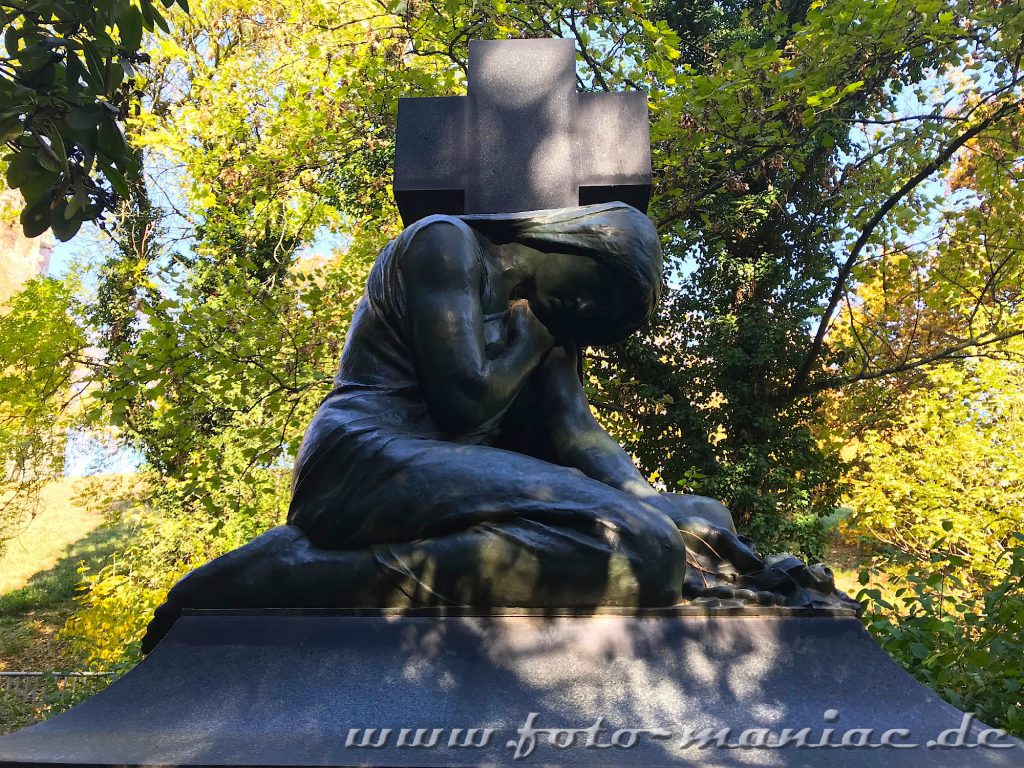 Eine trauernde Frau vor einem Kreuz auf dem Südfriedhof in Leipzig