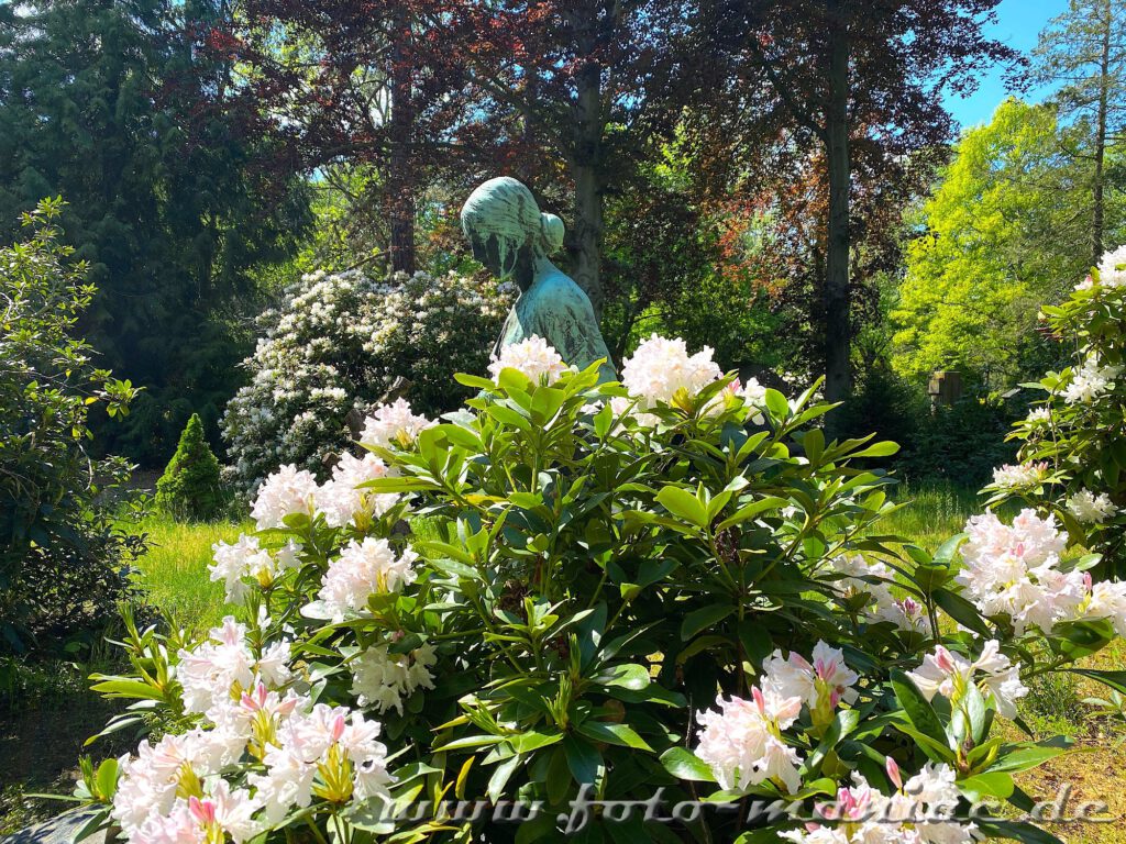 Bronze-Frau hinter Rhododendron-Busch auf Südfriedhof in Leipzig