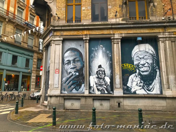 Drei Portraets auf einer Hauswand gehören zu Brüssels Schokloadenseiten