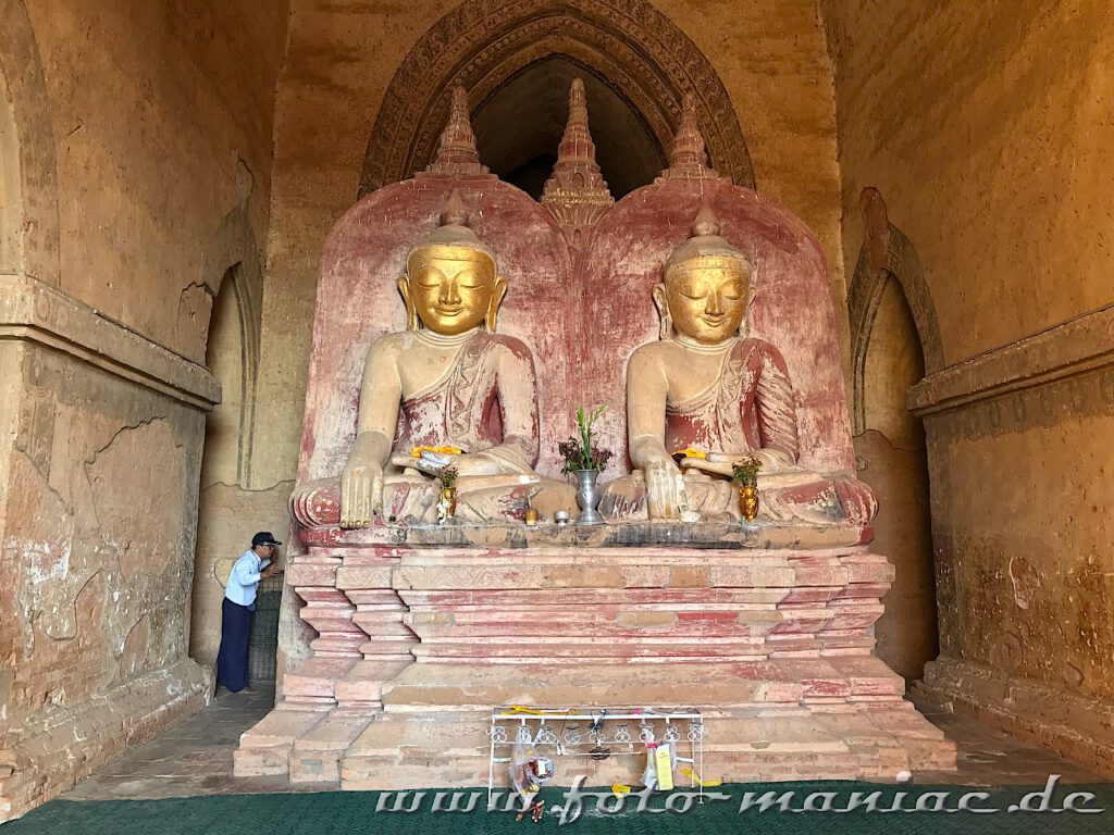 Einzigartige Tempelstadt Bagan - ein Mann schaut hinter die Buddhas im Dhammayangyi Tempel