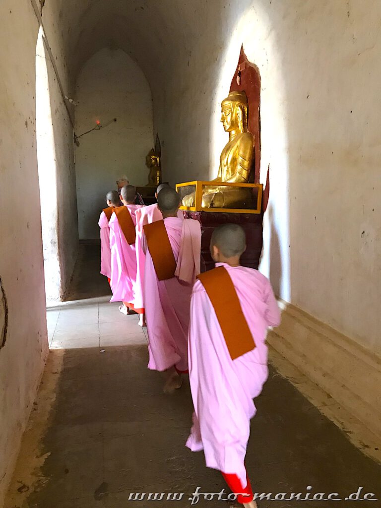 Einzigartige Tempelstadt Bagan - Nonnen laufen an einem goldenen Buddha vorbei