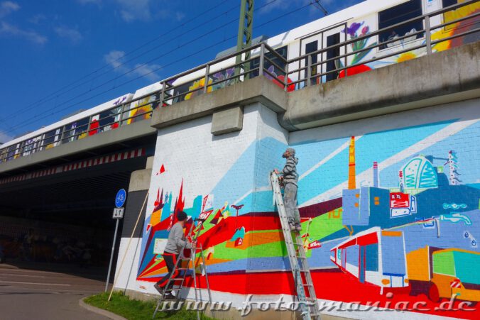 Zwei Streetart-Künstler bringen Graffito an Bahnbrücke an
