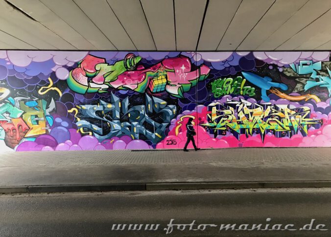 Frau läuft in einer Unterführung vor einem Graffito