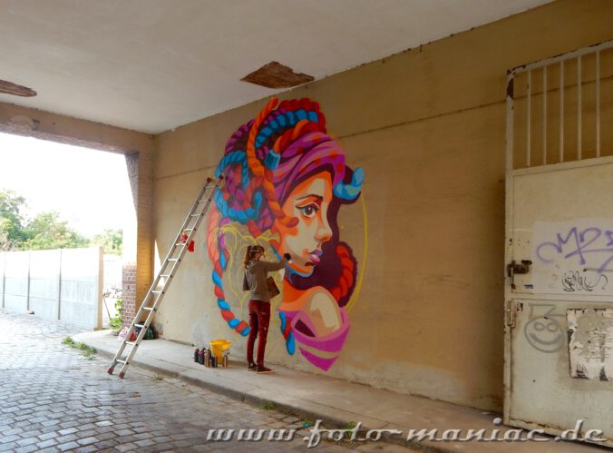 Künstlerin arbeitet in einem Toreingang an einem Frauenporträt