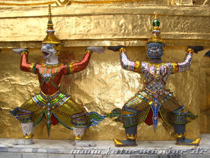 Thailands schmucke Juwelen - zwei üppig dekorierte Figuren an einem Palast-Gebäude