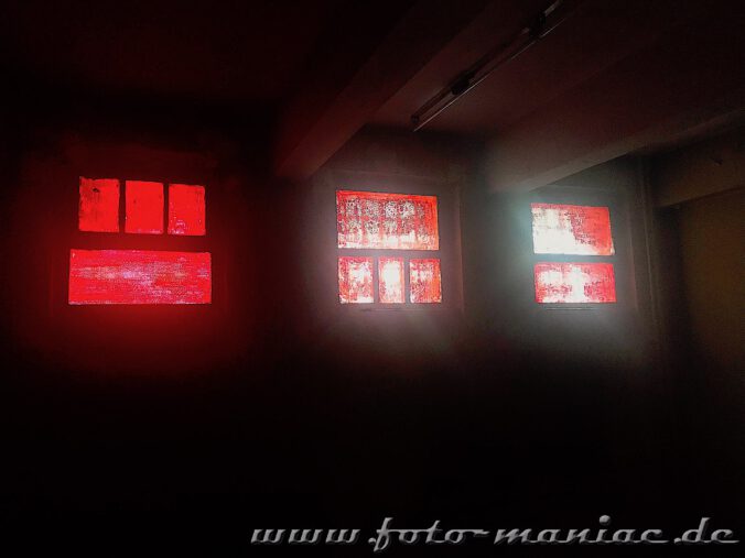 Licht fällt durch rotgestrichene Fenster