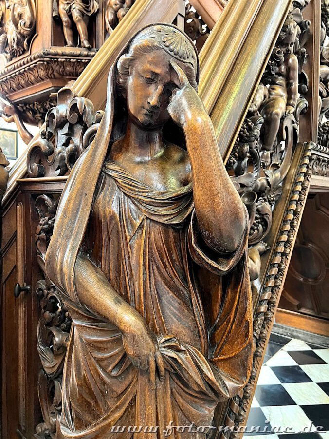 Geschnitzte Frauenstatue in der Kirche Walburga in Brügge tippt sich an die Stirn