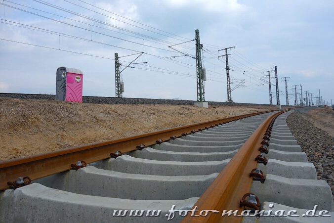 Zwischen zwei Schienensträngen steht ein rosafarbenes Mobil-Klo