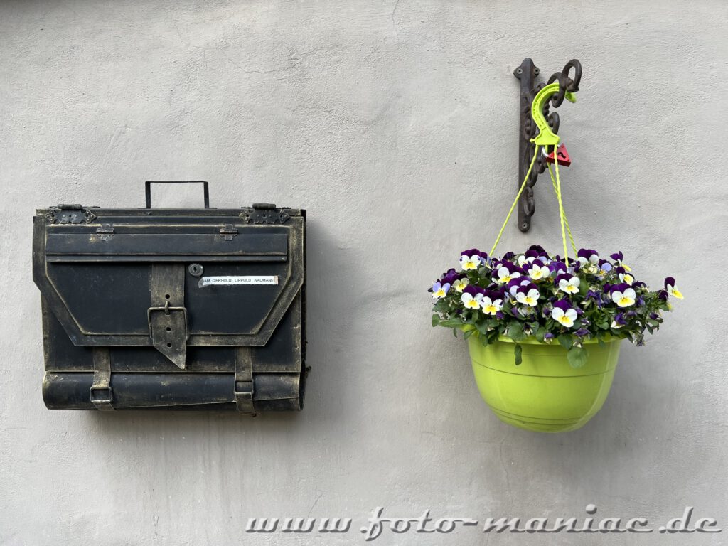 Briefkasten und Blumentopf an Fassade