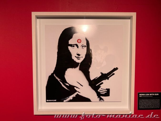 Mona Lisa mit Maschinengewehr hat roten Zielpunkt auf der Stirn