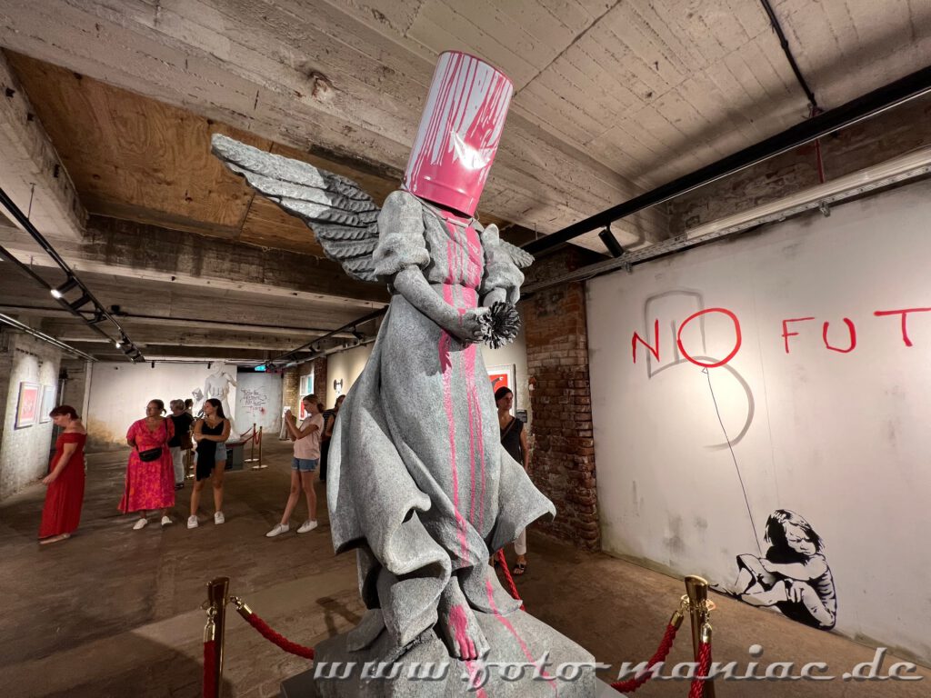 Banksy im Kunstkraftwerk Leipzig - Frau mit Flügeln und Farbeimer auf dem Kopf
