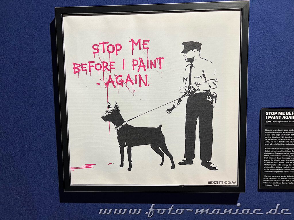 Hilfloser Polizist mit Hund vor einer Spayer-Botschaft an der Wand