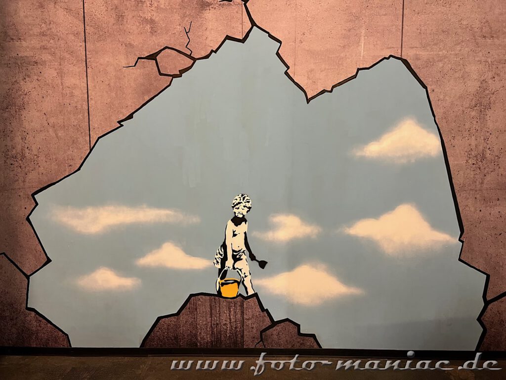 Junge mit Farbeimer auf einem Berg beim Himmel anstreichen