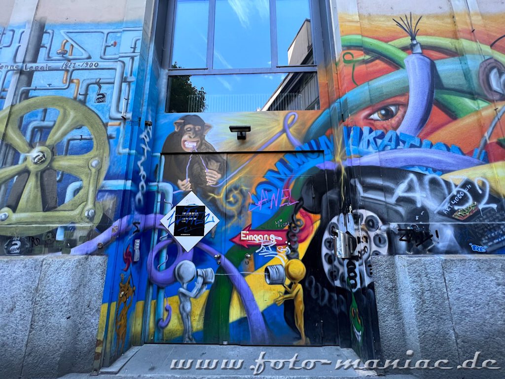 Affe und Rohre auf einer Graffitiwand in Basel