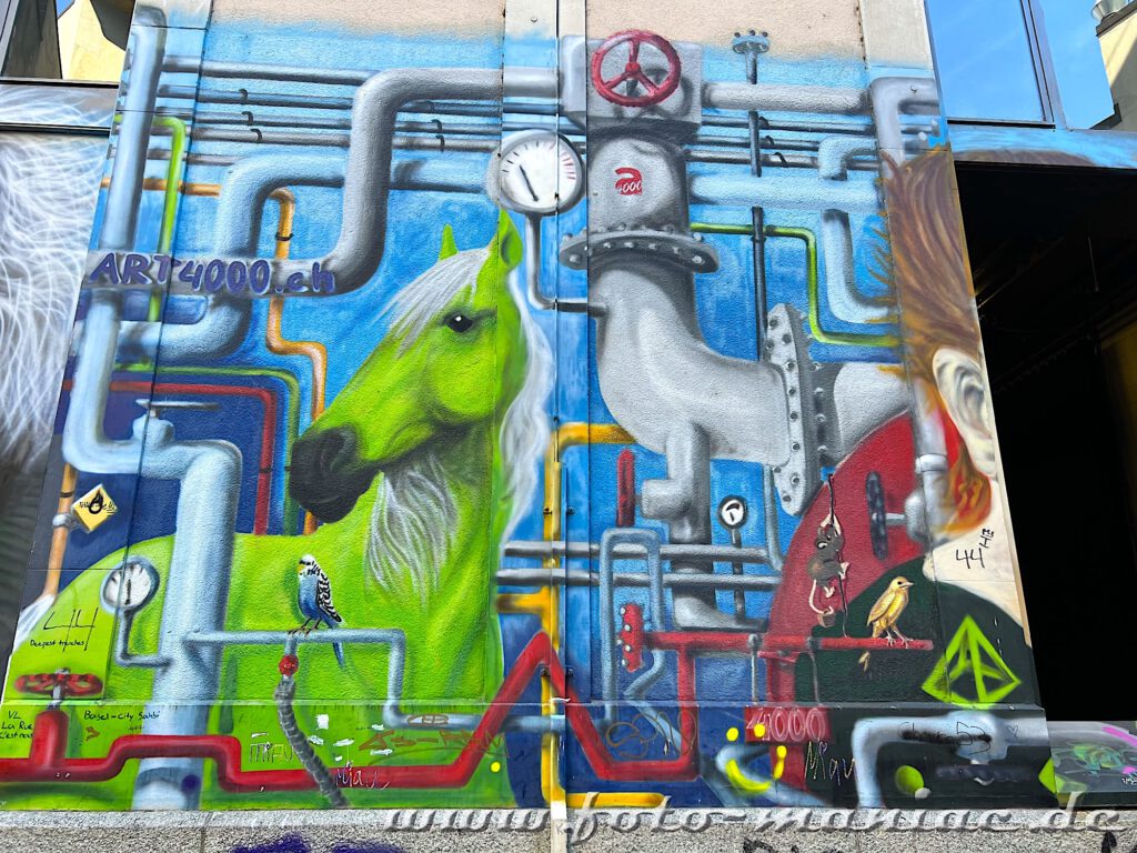 Grünes Pferd unter Rohrleitungen auf einer Graffitiwand in Basel