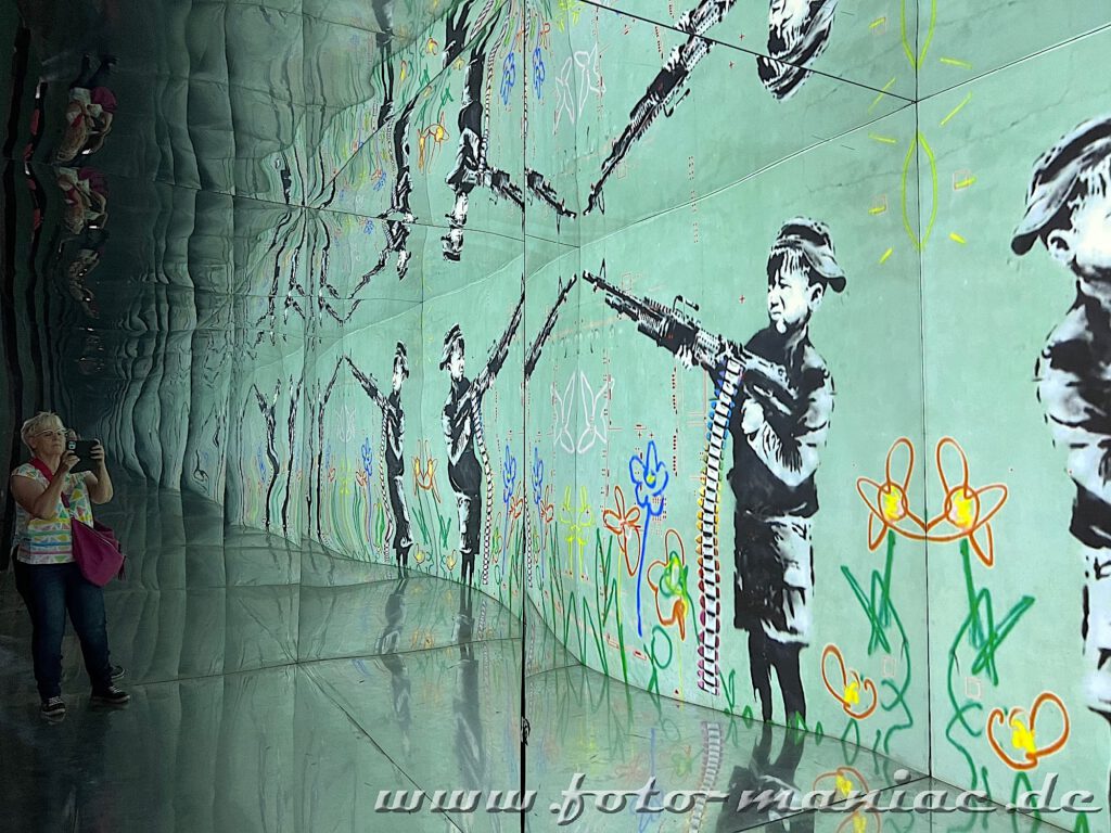 Banksy im Kunstkraftwerk - Spiegelung mit einem Jungen mit Maschinengewehr
