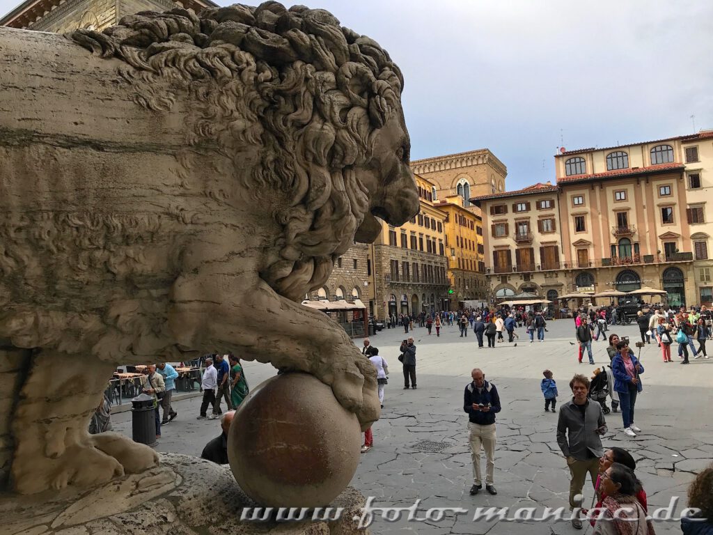 Ein steinerner Löwe stützt hoch über der Piazza della Signoria seine rechte Pranke auf eine Kugel