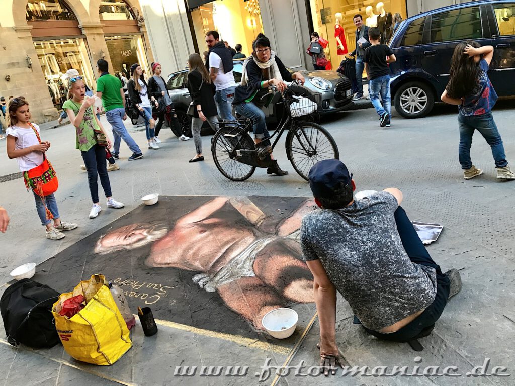Streetart-Künstler malt eine Männergestalt auf das Straßenpflaster von Florenz