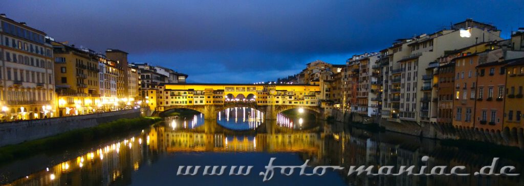 Kurzreise nach Florenz: Die beleuchtete Ponte Vecchio spiegelt sich am Abend im Wasser des Arno