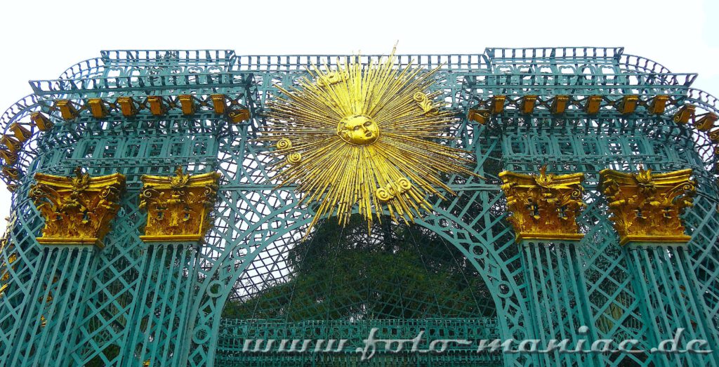 Eine goldene Sonne strahlt am grünen Gitterpavillon von Schloss Sanssouci