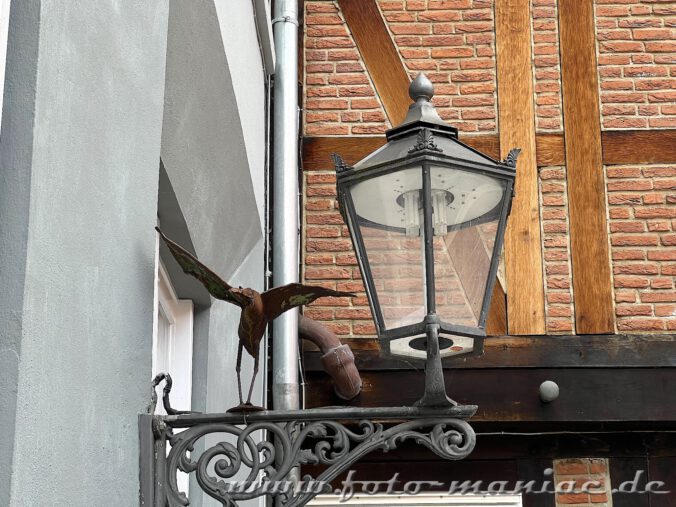 Vogelskulptur mit ausgebreiteten Flügeln auf einer Straßenlaterne in Celle