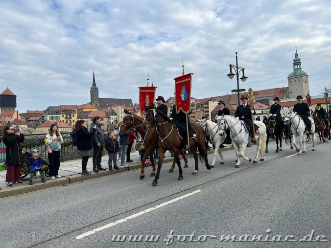 Die Osterreiter von Bautzen ziehen mit Fahnen über die Friedensbrücke der Stadt